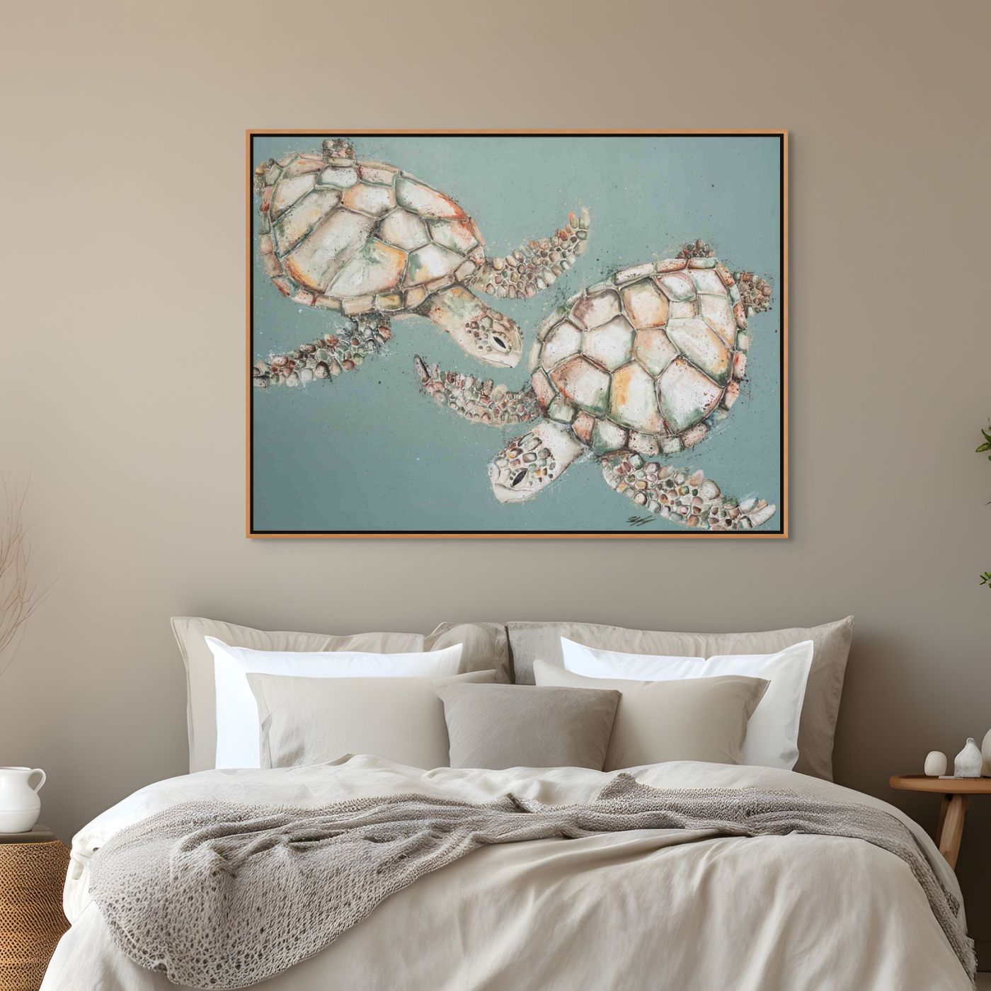 Framed artwork of two turtles on a wall above a bed with neutral bedding.